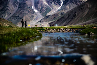 a couple of people standing on a cliff above a lake