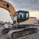 Woman operator confidently steering a loader across rugged terrain under a cloudy sky.