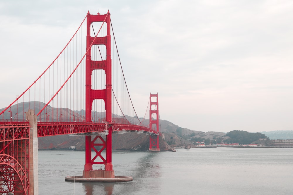 a red bridge over water with Golden Gate Bridge in the background