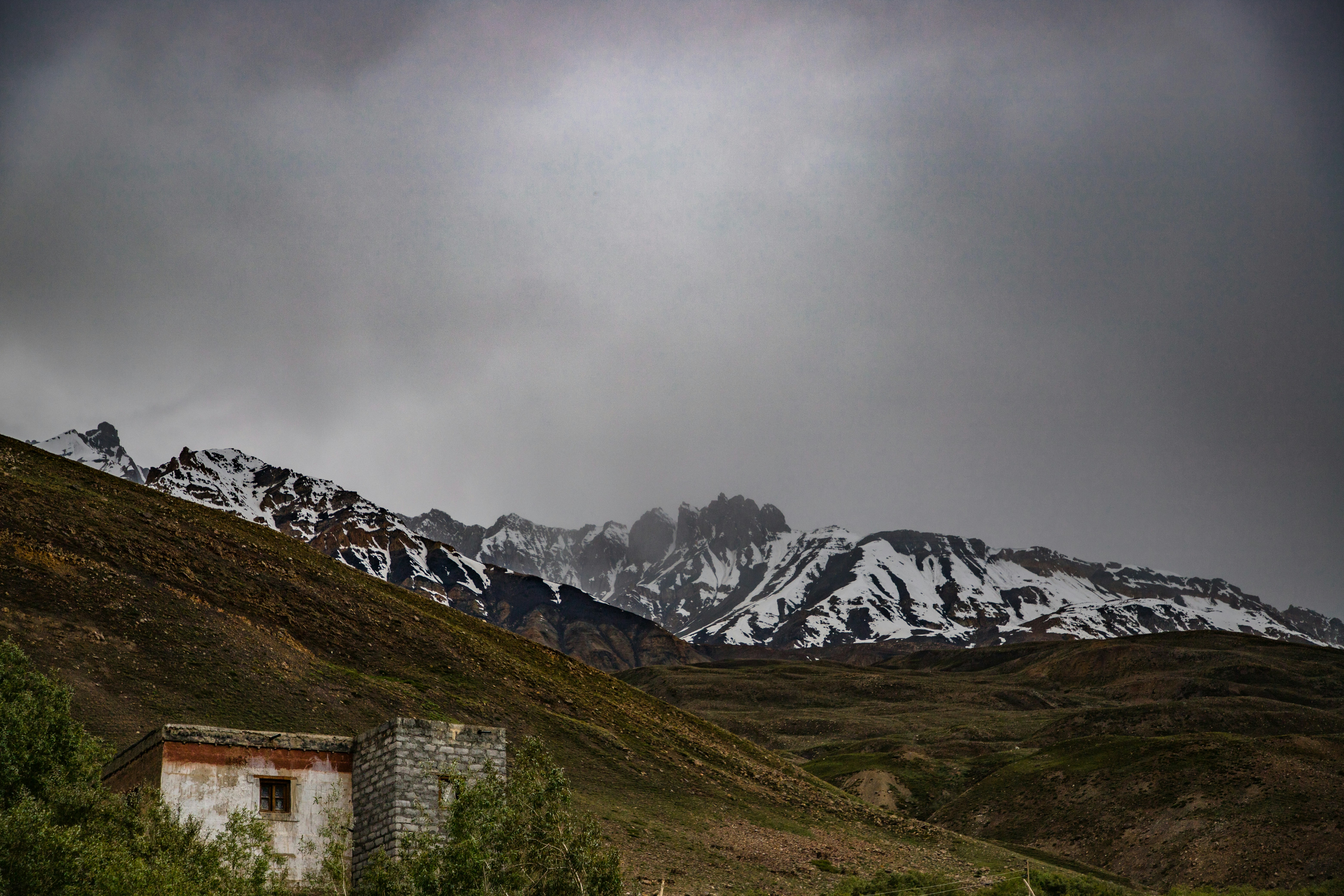 a building on a hill with snowy mountains in the background