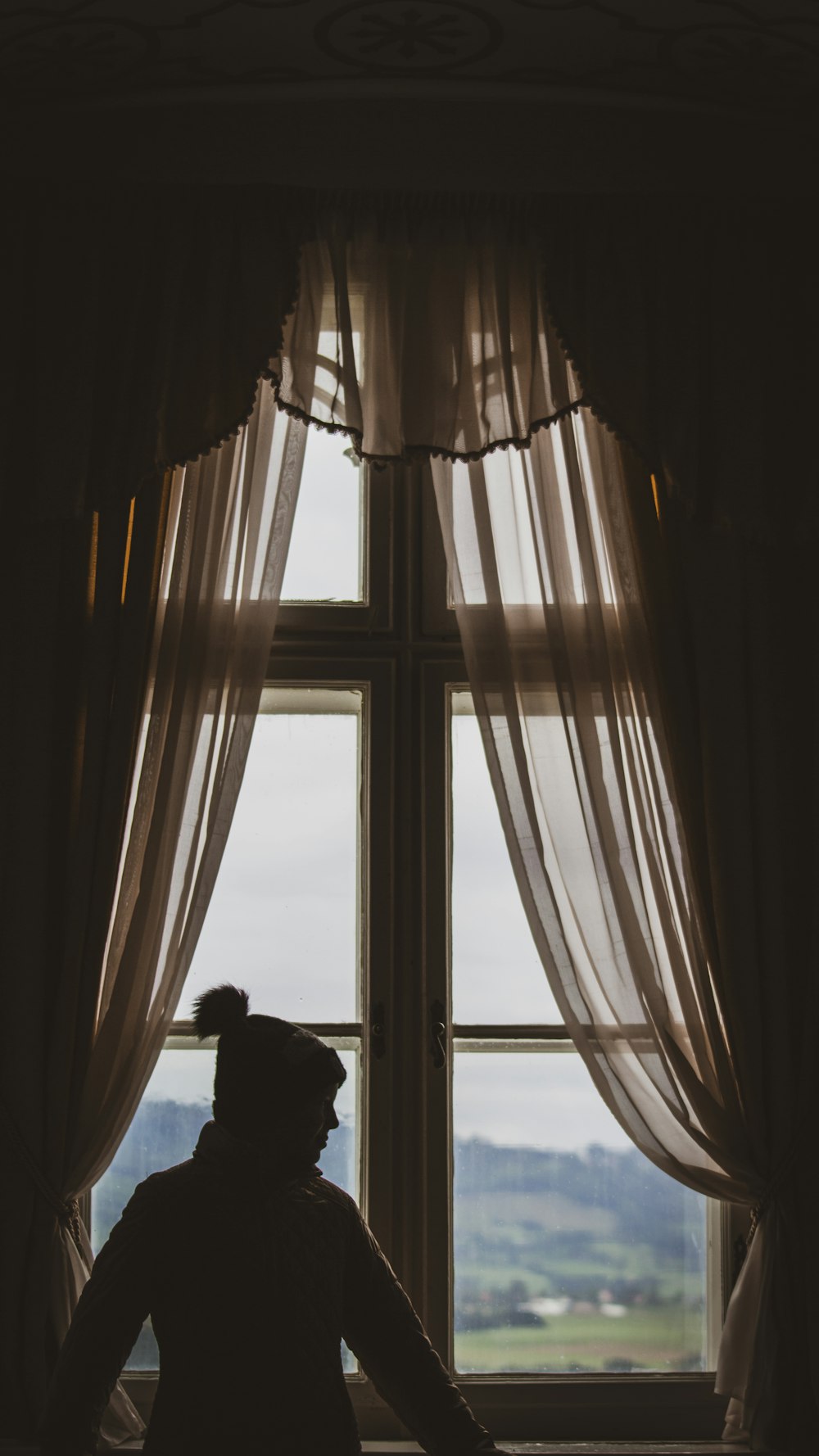 a silhouette of a man and woman looking out a window