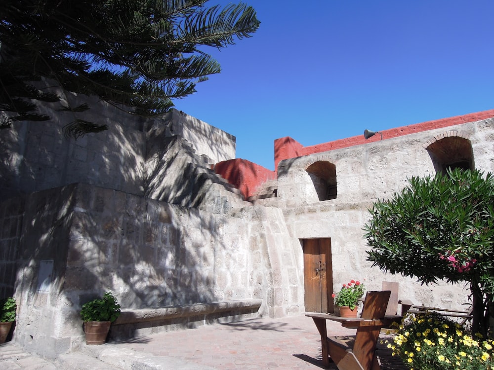 a stone building with a bench and a tree in front of it