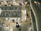 An aerial view of a modern retail store interior featuring neatly arranged displays of clothing, accessories, and mannequins. The store is well-lit with a sleek design, and several shoppers are visible browsing the merchandise. Glass and metal elements contribute to the contemporary aesthetic.