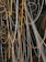 A complex network of illuminated cables and wires suspended from the ceiling, displaying a mix of orange and white glows. The cables intertwine and loop in various directions against a backdrop of a modern industrial interior featuring exposed beams and metal structures.