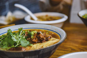Close-up of a savory bowl of sop iga with rich broth and tender meat garnished with fresh herbs