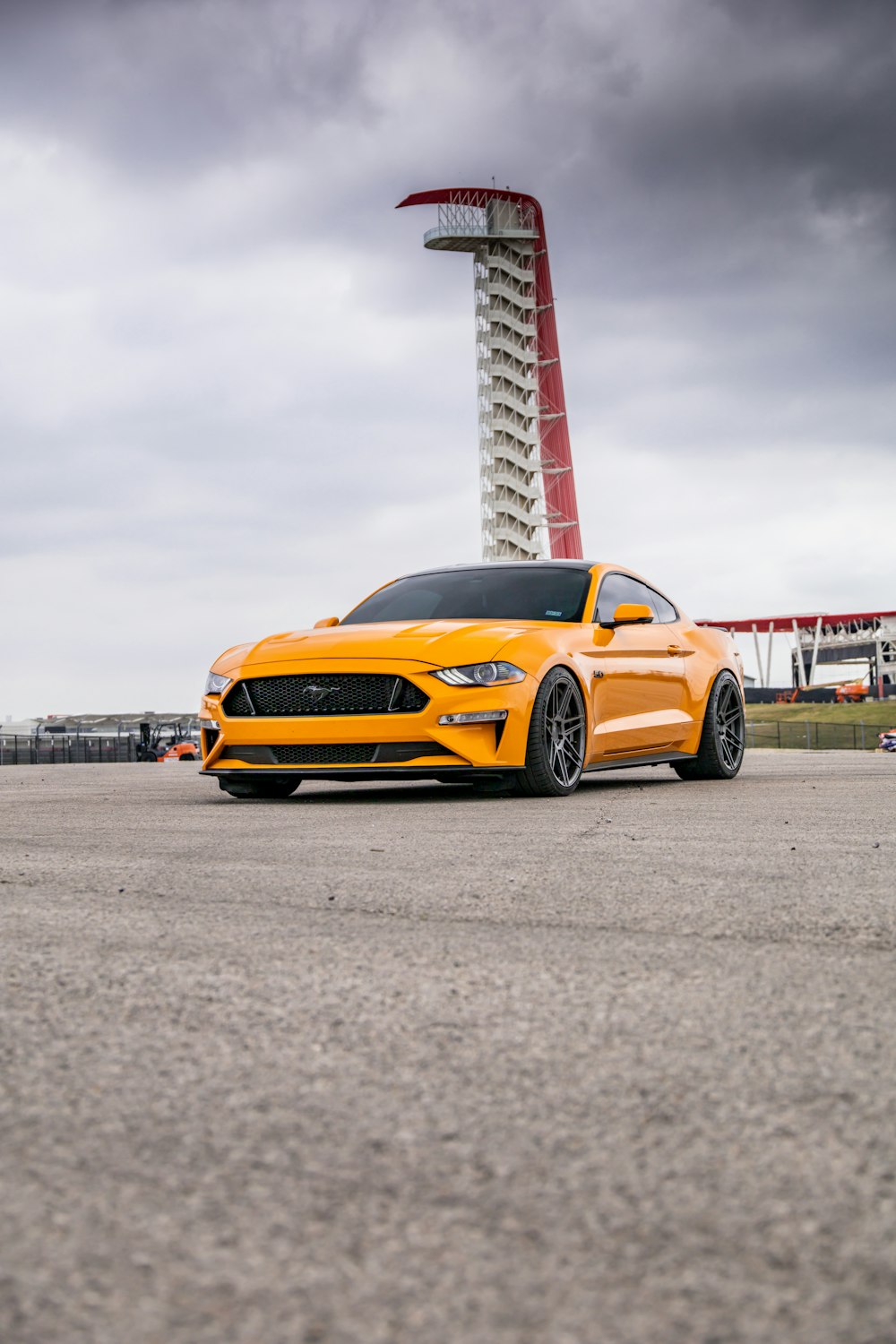 a yellow sports car parked in front of a tower