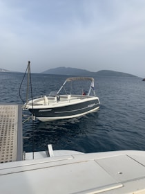 Technician inspecting a boat engine on a dock under clear skies.
