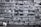 A multi-story residential building features numerous apartments with balconies. Each unit is fitted with air conditioning units attached below the windows. The facade exhibits a uniform pattern of windows and concrete, creating a repetitive architectural style.