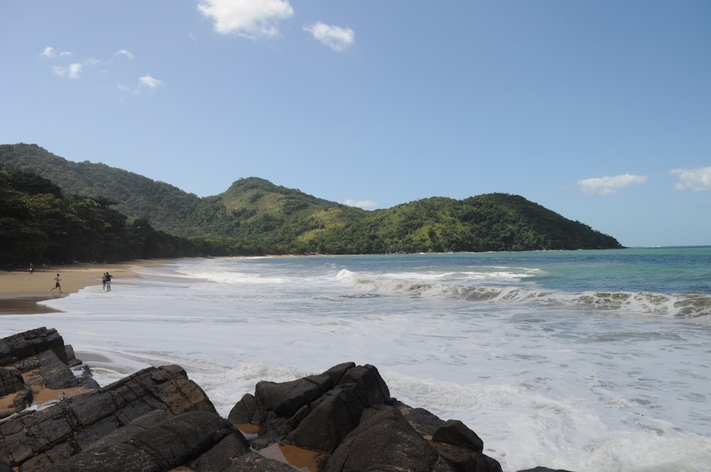 a beach with rocks and a hill in the background