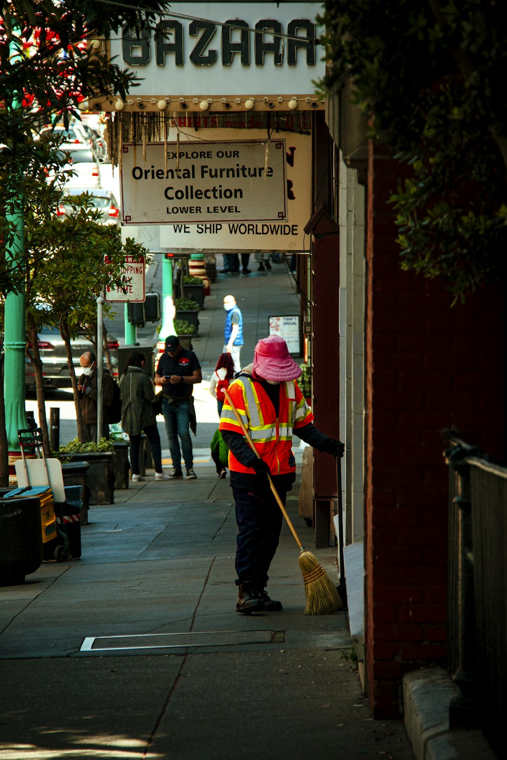 a person in a red vest sweeping the street