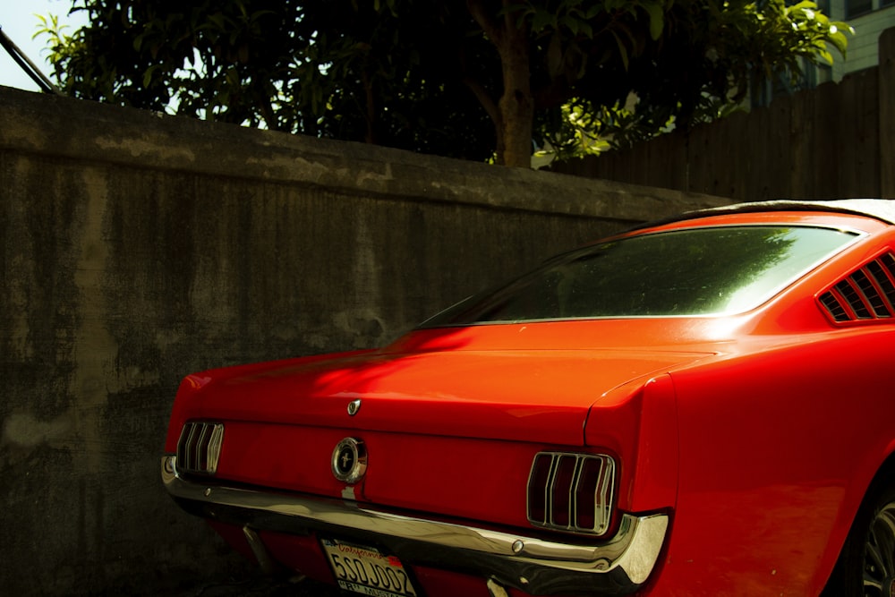 a red car parked next to a wall