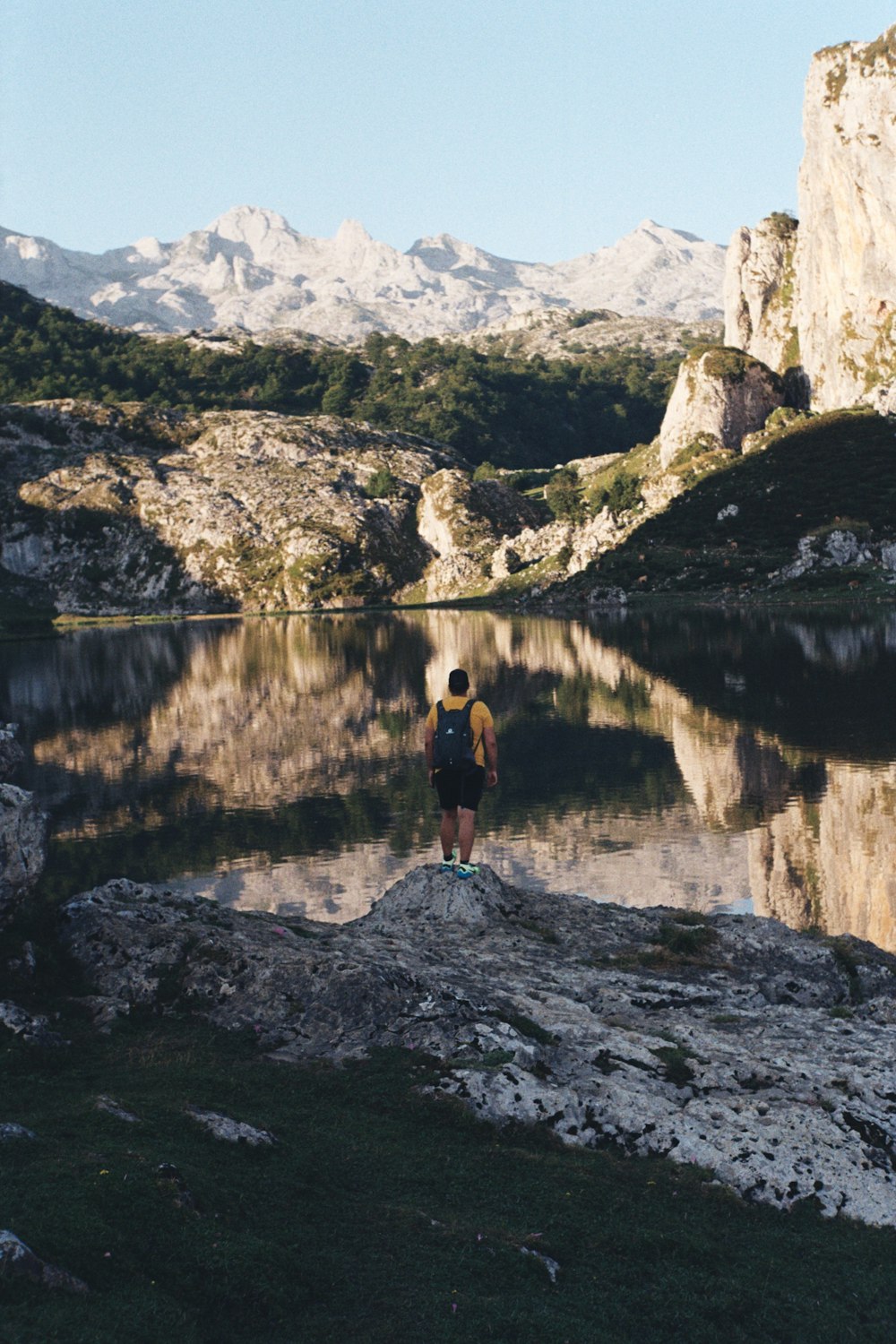 a person standing on a rock in front of a lake
