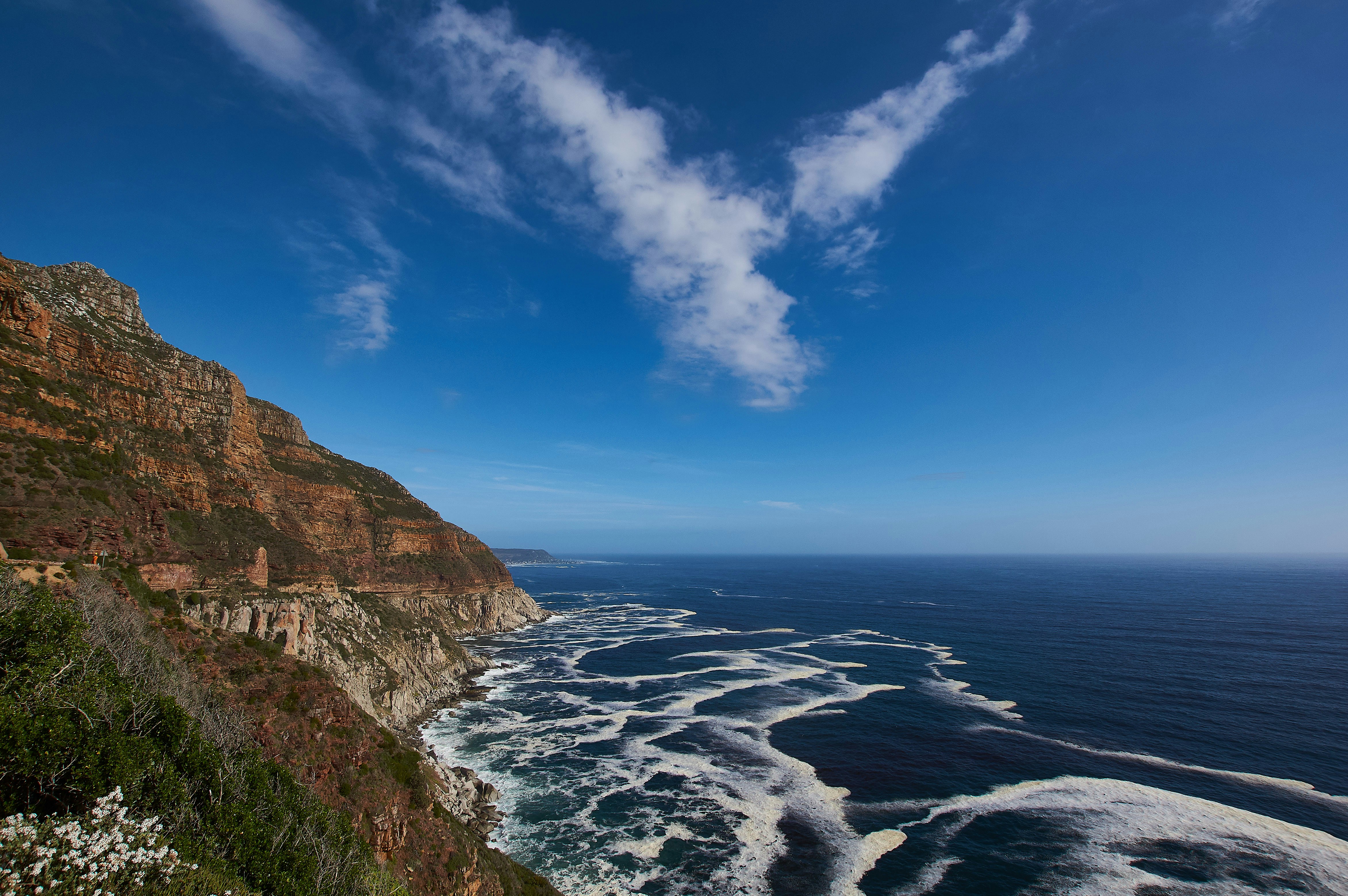 a rocky beach with a cliff and blue sky