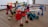 A group of colorful, articulated robot figures made from interlocking plastic pieces is arranged on a wooden floor. Each figure features distinct colors and shapes, with some resembling vehicles or animals equipped with mechanical limbs. The scene is playful and dynamic, showcasing a variety of textures and designs.