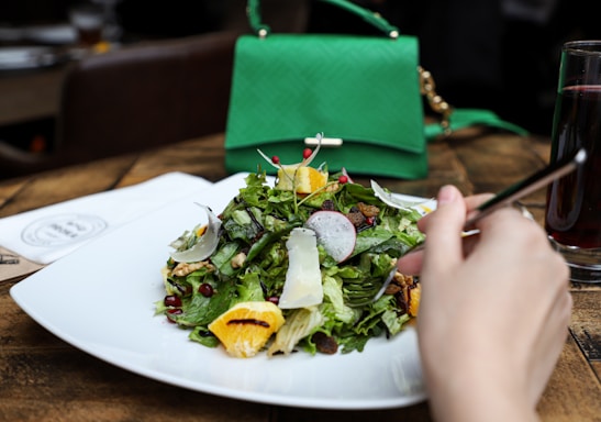 a hand holding a plate of salad