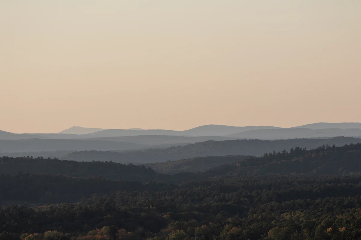 Rolling wooded hills fading into layers at dusk in autumn