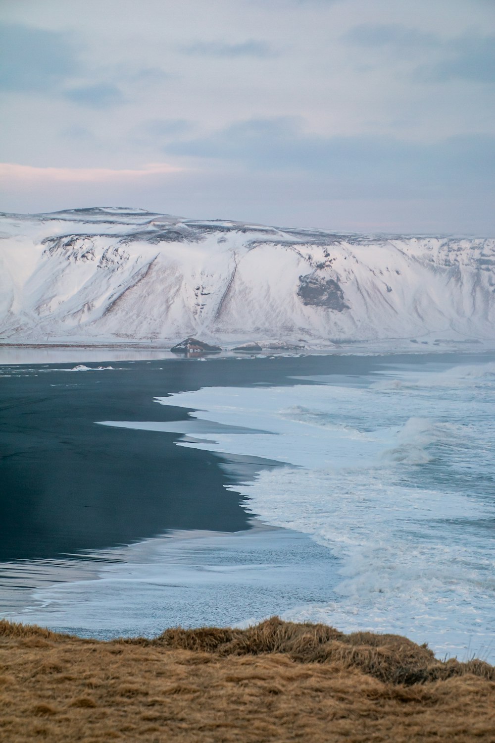 a body of water with a snowy mountain in the background