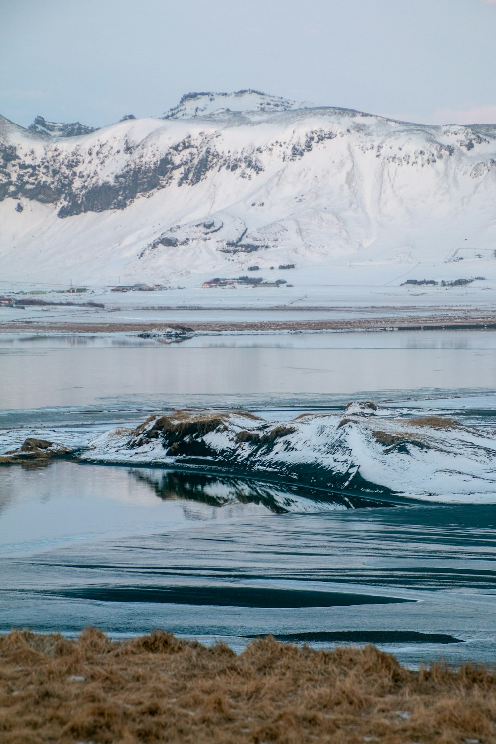 a body of water with snow covered mountains in the background