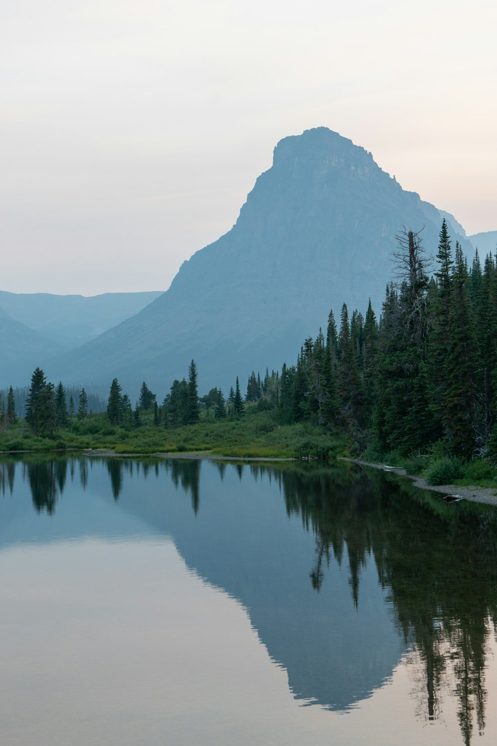 a lake with trees and mountains in the background