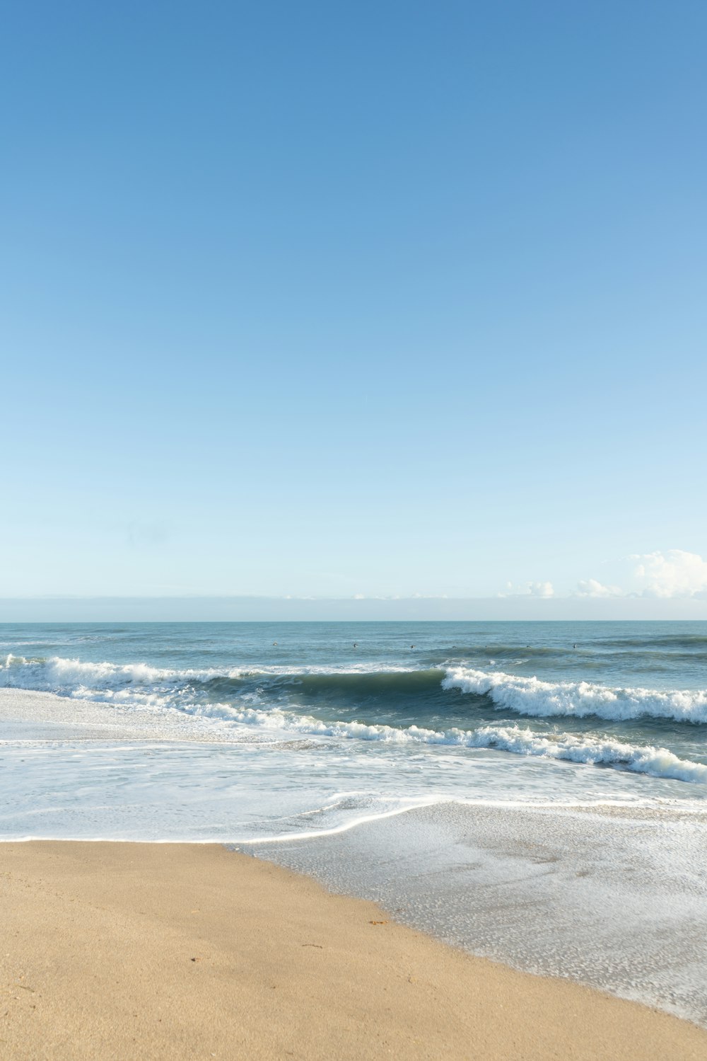 a beach with waves and blue sky