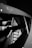 A close-up view of a car interior focusing on a sleek, modern seat design with a prominent logo or emblem on the headrest. The image is in black and white, highlighting the contrast and details of the seat's texture and structure.
