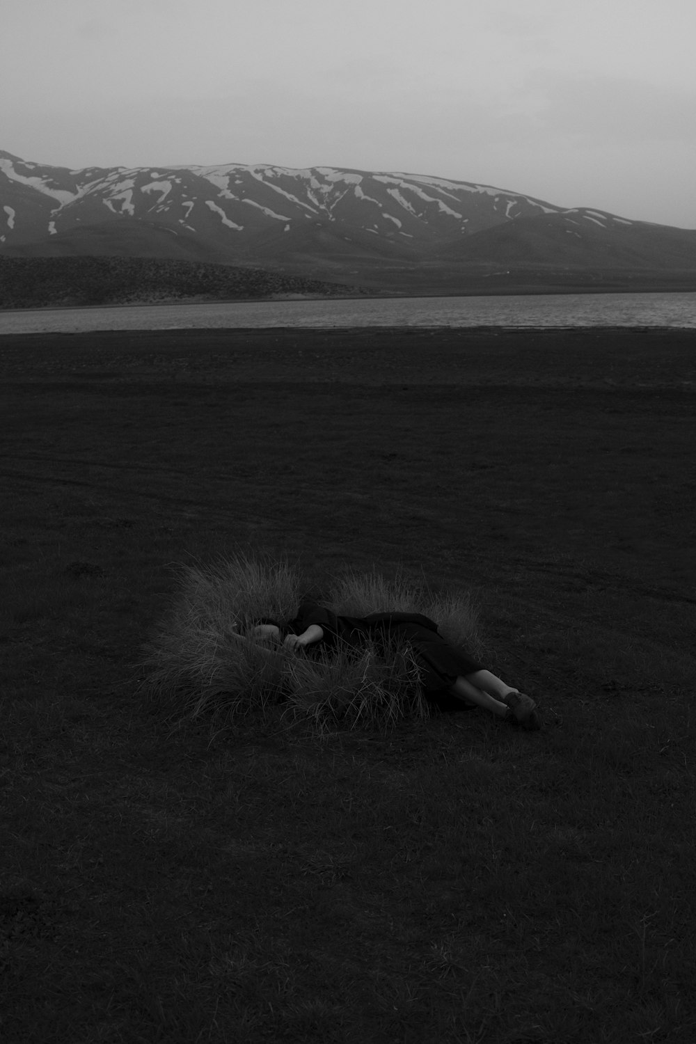 a person lying on the ground with a body of water in the background