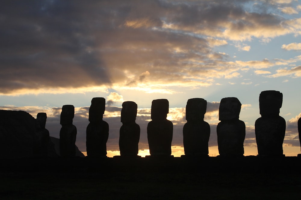 a group of people sitting in a row in front of a sunset with Stonehenge in the background