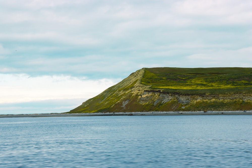 a body of water with a hill in the background