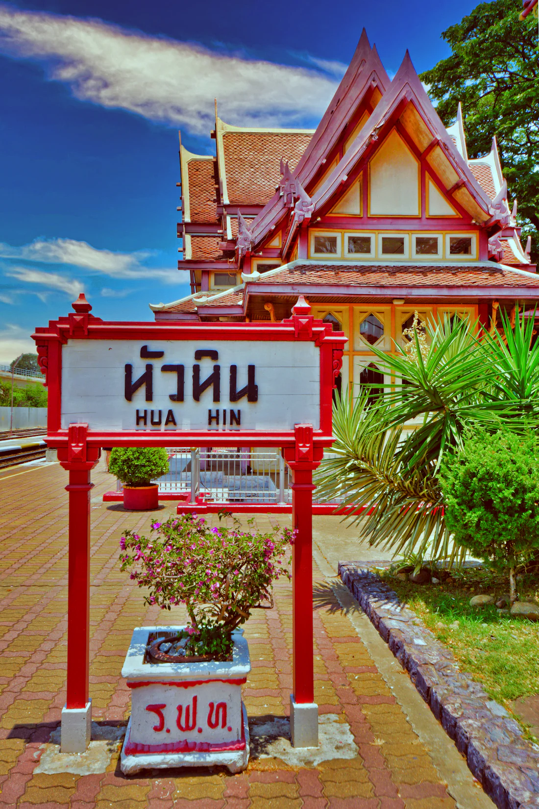 ป้ายสถานีรถไฟหัวหิน ตัวอักษรไทยและอังกฤษบนกรอบสีแดง ข้างอาคารสถานีไม้