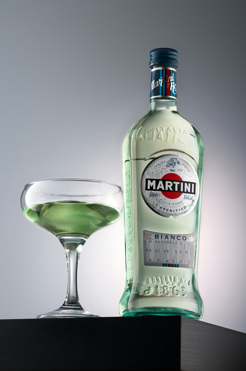 a bottle of alcohol next to a glass of green liquid