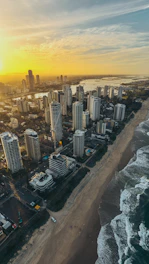Aerial view of Cabo Frio coastline with golden sunset reflecting on the ocean and cityscape in the background