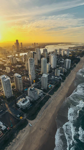 Aerial view of Cabo Frio coastline with golden sunset reflecting on the ocean and cityscape in the background