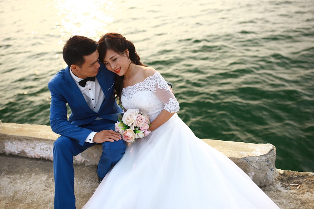 a man and woman sitting on a bench with a bouquet of flowers