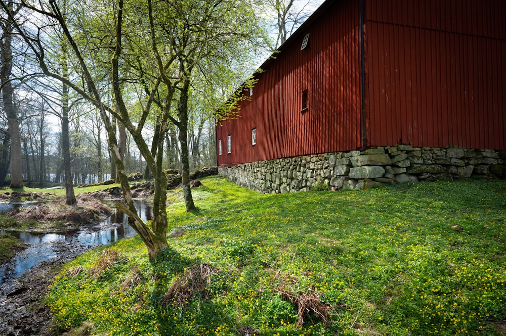 a red barn next to a stream
