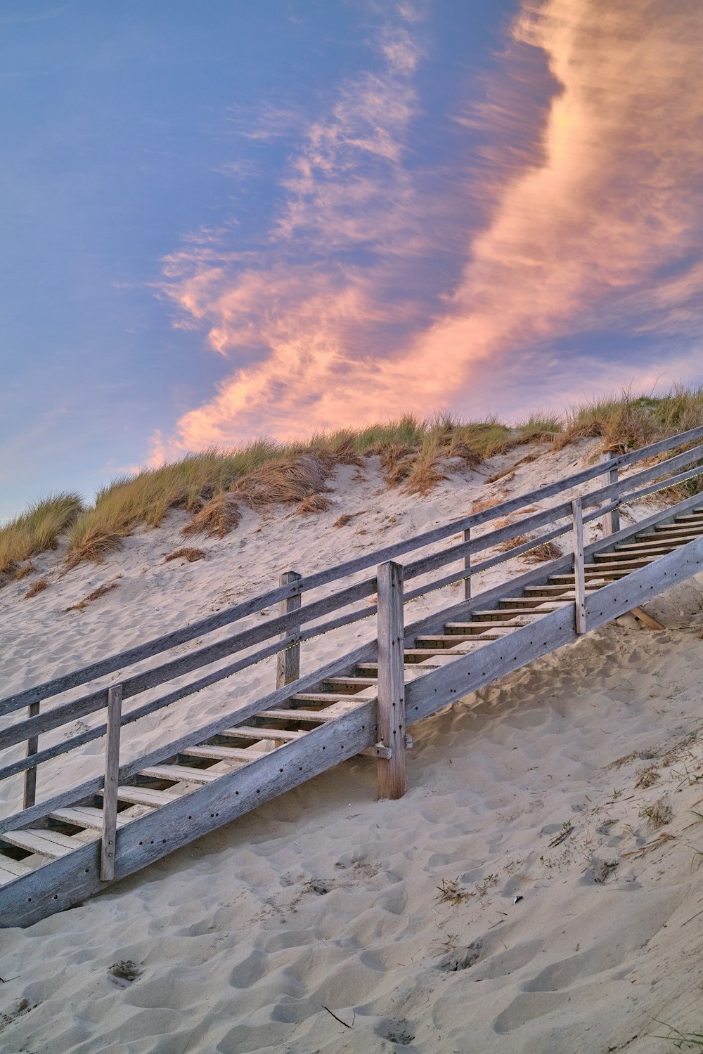 uma escadaria de madeira em uma praia de areia
