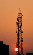 A tall telecommunications tower rising against a sunset backdrop.