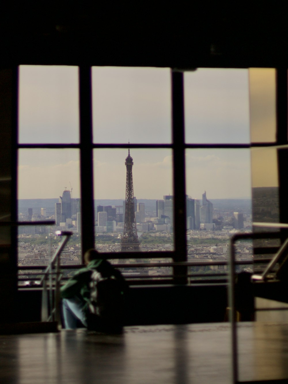 a person sitting on a bench looking out a window at a city