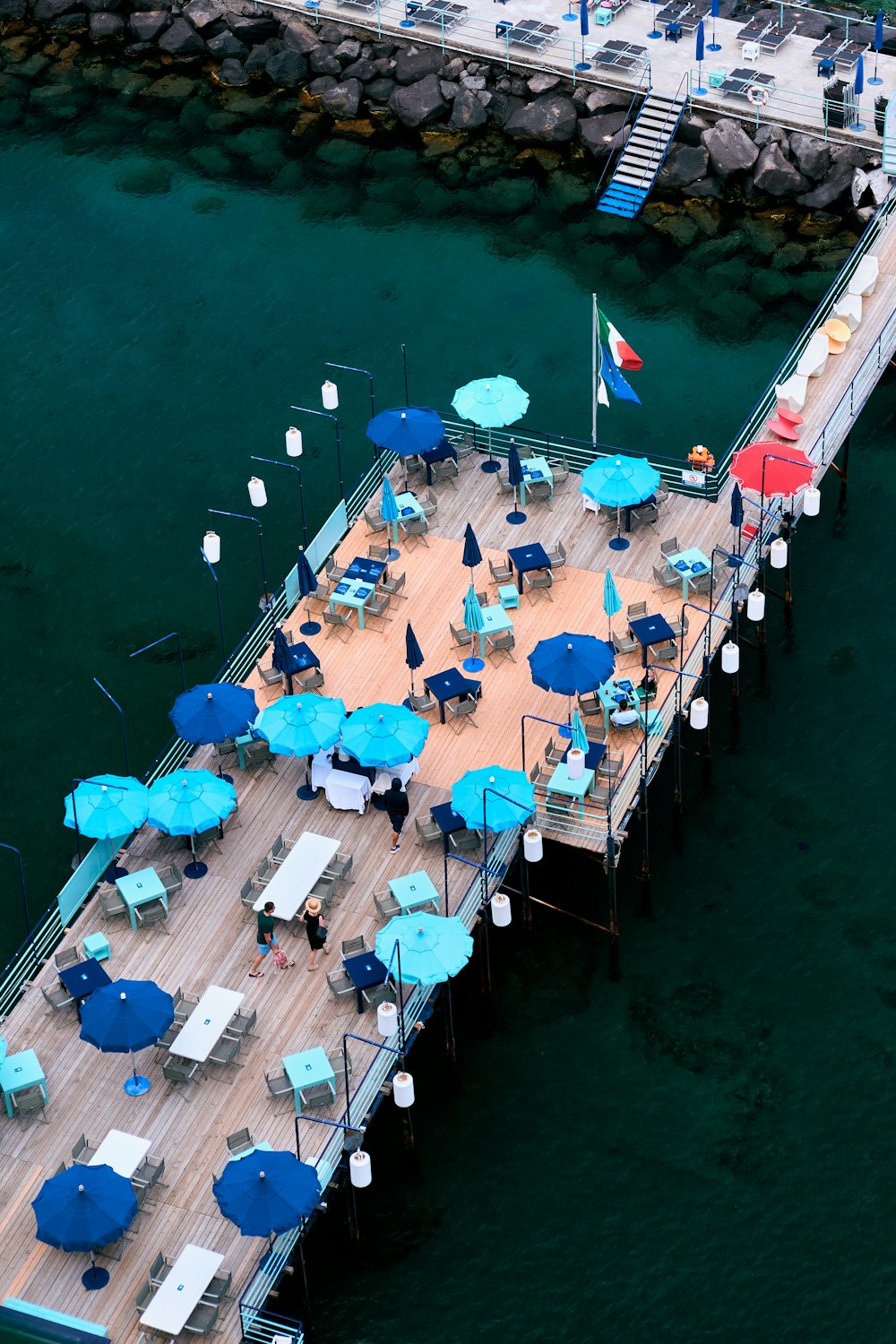 a group of people sitting on a dock with umbrellas