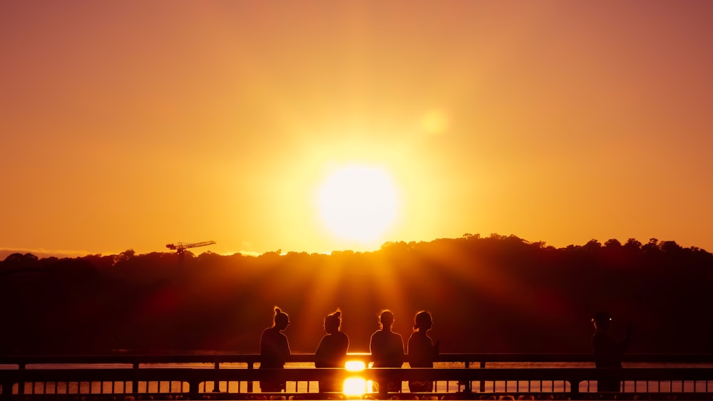 a group of people sitting on a bench looking at the sun