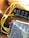 A close-up view of electronic components including a power distribution board labeled 'Moraydular Power Bus Wide V1' and a metal perforated cover. Yellow wires are connected to various terminals, lying on a wooden surface.