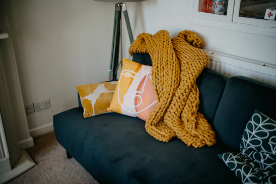 A warm, inviting living room showcasing soft cushions and throws from texturaviva's collection.