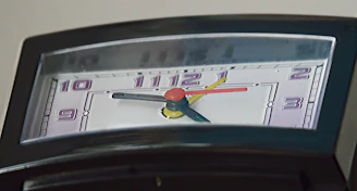 Close-up of a quirky clock with mismatched numbers and colorful hands.