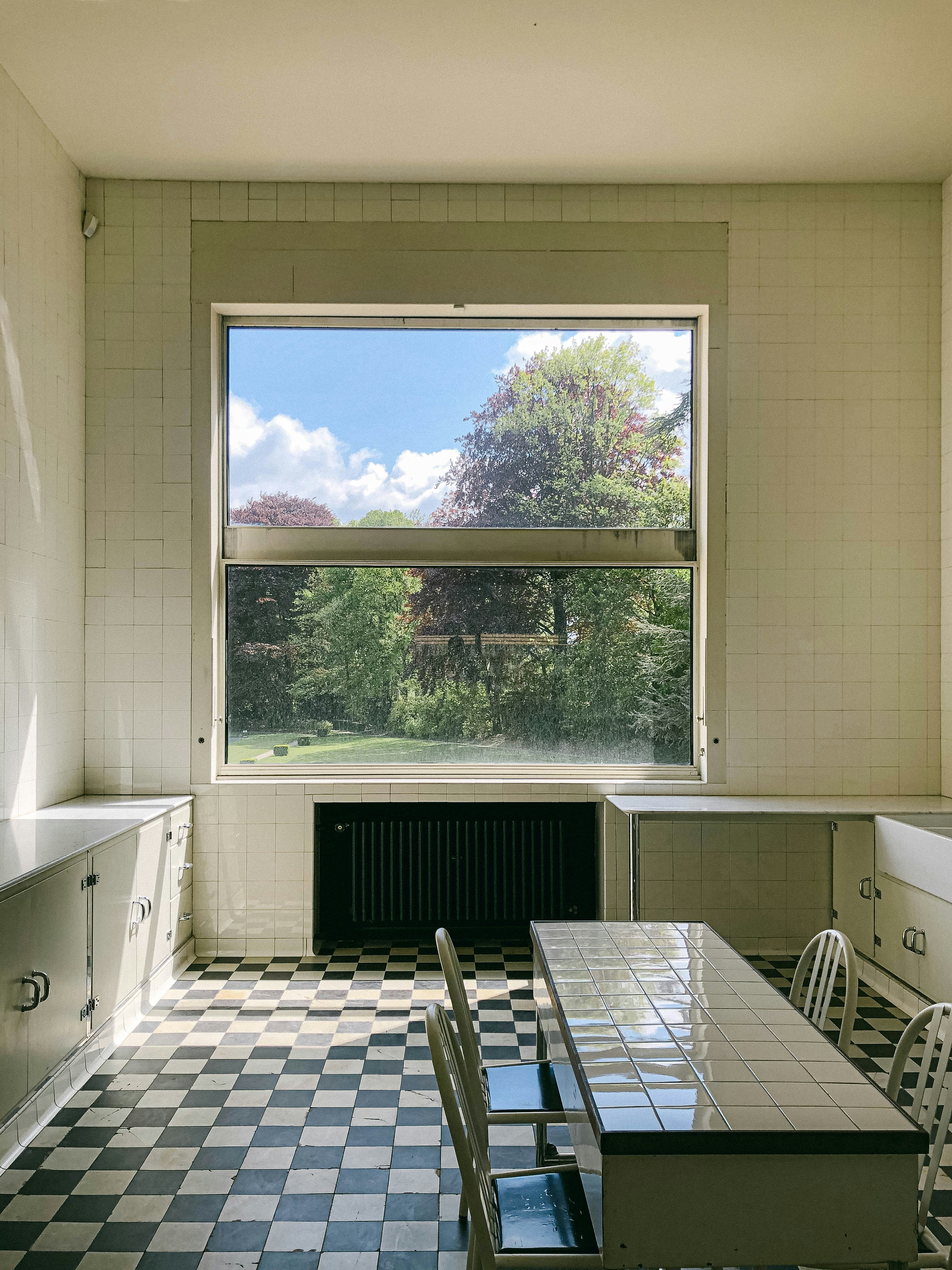 Empty room with checkerboard floors and garden view.
