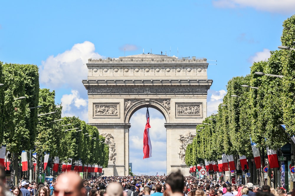 a large group of people in front of a large stone arch with Arc de Triomphe in the background