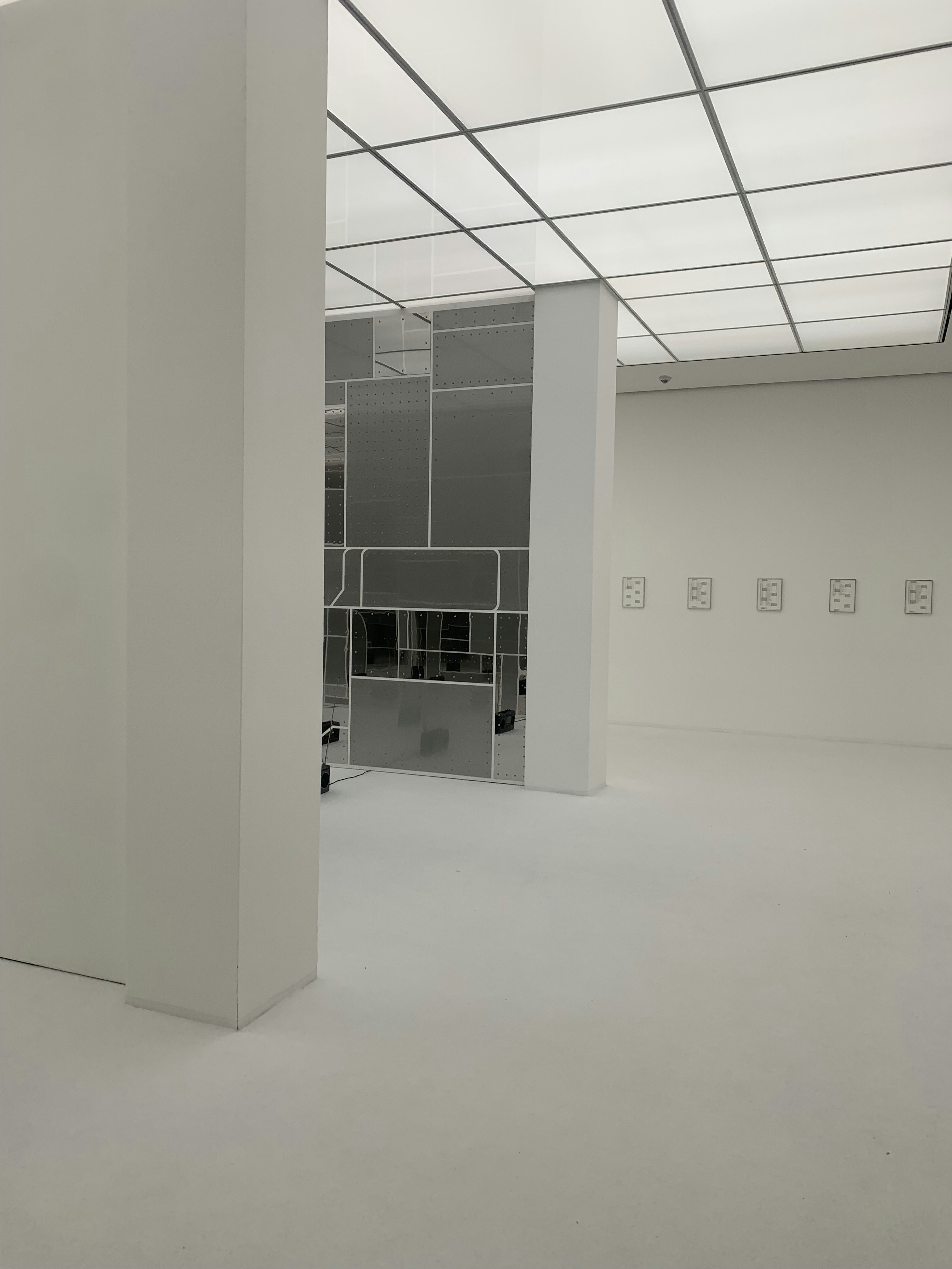 Minimalist gallery-home interior with rammed earth walls and precisely angled skylights casting beams of light