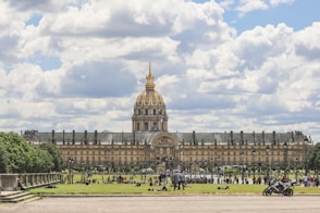 a large building with a gold domed roof and a crowd of people with Les Invalides in the background