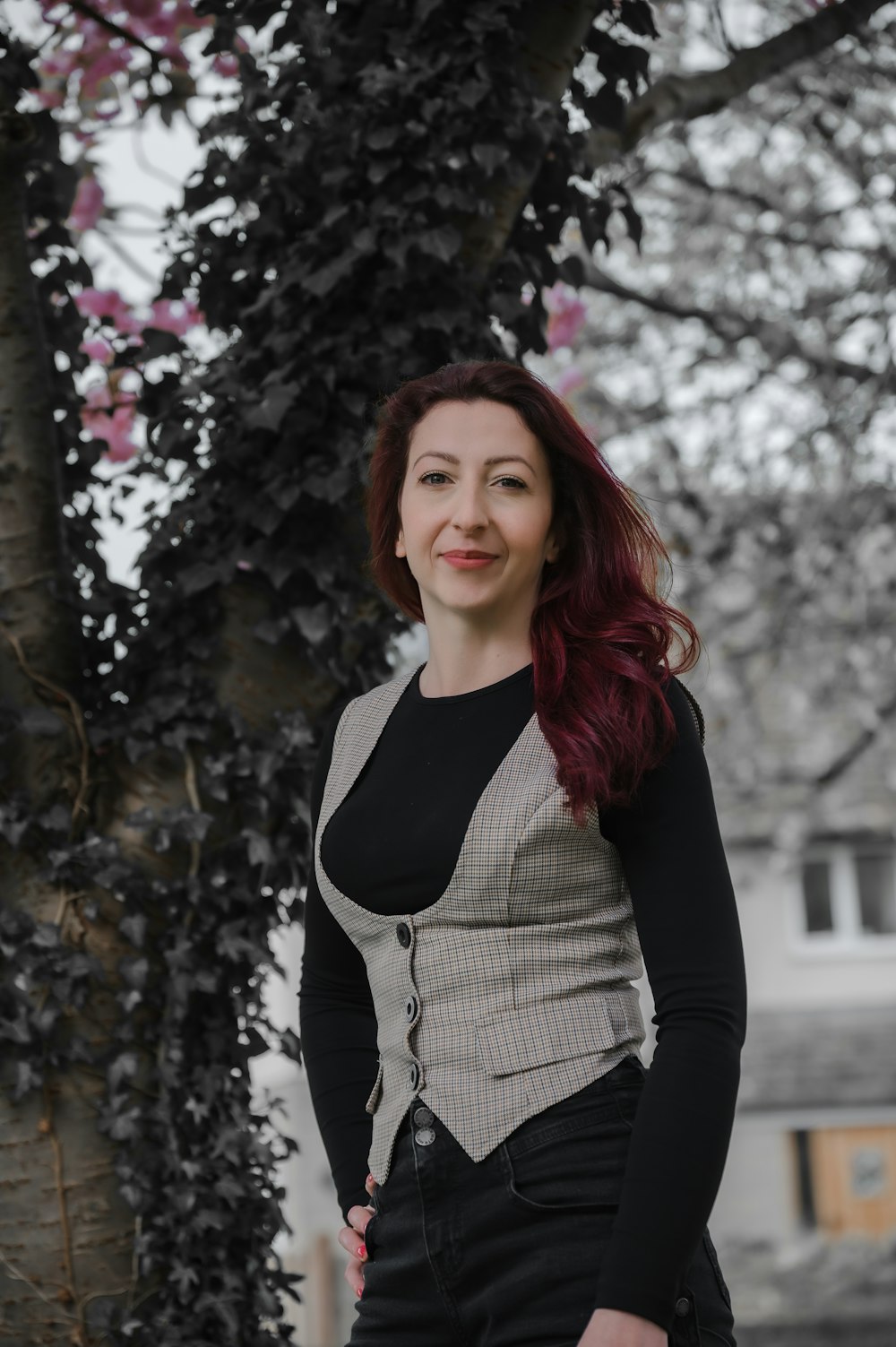 a woman standing in front of a tree with pink flowers