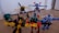 A group of colorful toy robots arranged on a wooden floor, featuring vibrant colors and intricate designs. Each robot is made of interlocking pieces in various poses, showcasing imaginative play. The scene captures a dynamic and playful moment, with toys spread out across the floor.