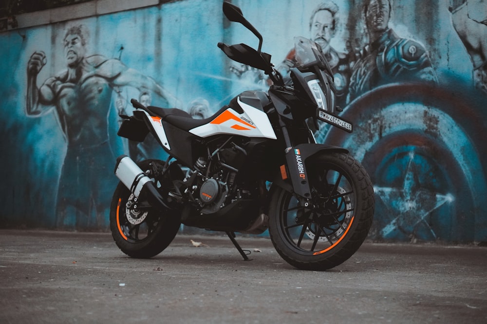 a motorcycle parked in front of a wall with graffiti