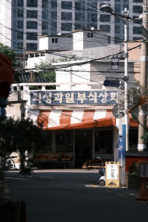 Front view of a small neighborhood grocery store with fresh produce displayed outside.